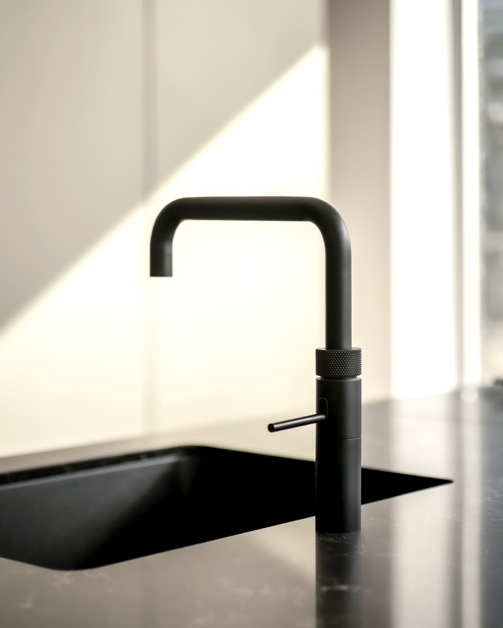 A black angular Quooker tap over a black sink